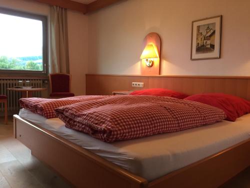 a bedroom with two beds with red sheets and a window at Gästehaus Schröder in Ruhpolding