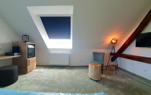 ein Wohnzimmer mit einem Dachfenster und einem TV in der Unterkunft Hotel Le Filou in Hille
