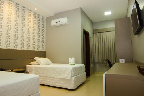 um quarto de hotel com duas camas e uma televisão em Hotel Mandino em Lucas do Rio Verde
