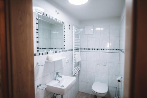 a white bathroom with a sink and a toilet at SennHOF Lechtal in Bach