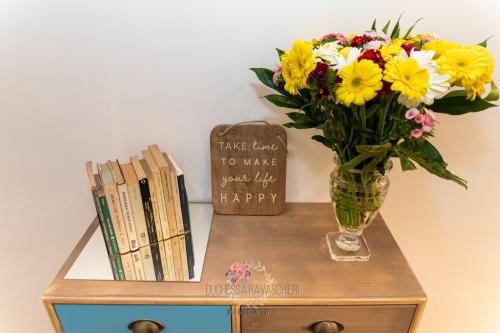 a vase of flowers on a table with books at Duchessa Ravaschieri bed and breakfast in Naples