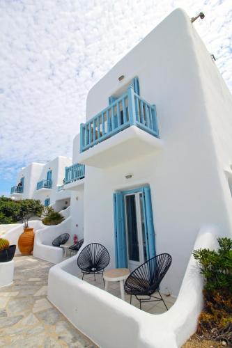 a row of white buildings with blue doors and chairs at Harmony Boutique Hotel in Mýkonos City