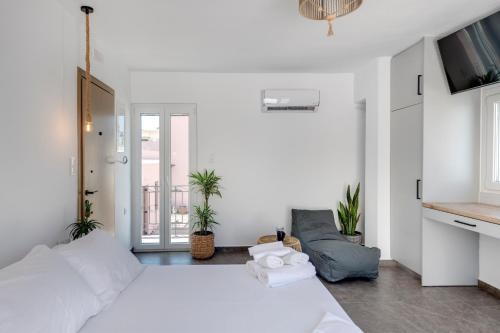 a white bedroom with a large bed and a balcony at Theogonia in Ermoupoli
