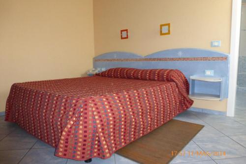 a bedroom with a bed with a red comforter at Hotel Chentu Lunas in Cagliari