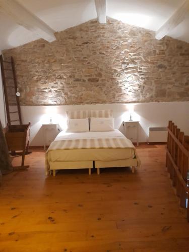 une chambre avec un lit et un mur en pierre dans l'établissement Le gîte de Sainte Valière PISCINE,SPA et CLIMATISATION, à Sainte-Vallière