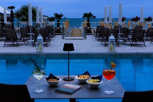 a table with wine glasses and snacks next to a pool at Hotel Cavalieri Palace & Suites in Lido di Jesolo