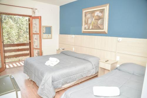two beds in a room with blue walls at Terrazza Hotel in Campos do Jordão