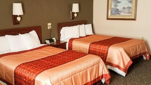 una camera d'albergo con due letti con lenzuola arancioni di Ivey's Motor Lodge a Houlton