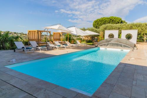 une piscine avec chaises et parasols dans une cour arrière dans l'établissement Domaine 669, Villa contemporaine et de prestige, à Alès