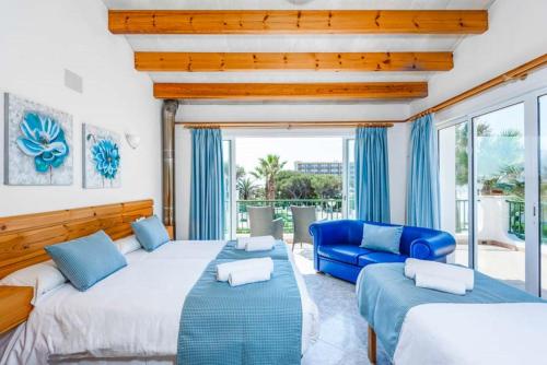 a bedroom with two beds and a blue couch at Villa SOFIA in Cala en Forcat