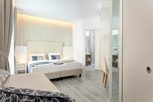 a hotel room with two beds and a desk at Hotel Cavalieri Palace & Suites in Lido di Jesolo