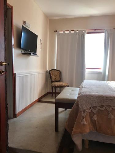 a bedroom with a bed and a chair and a television at LOS TEROS POSADA DE CAMPO in San Rafael