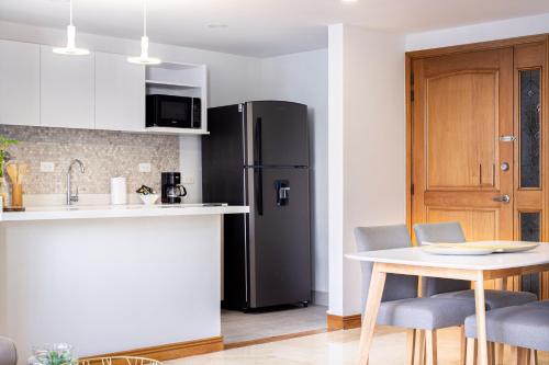 a kitchen with a table and a refrigerator at Alcazar de Oviedo by EE Hoteles in Medellín