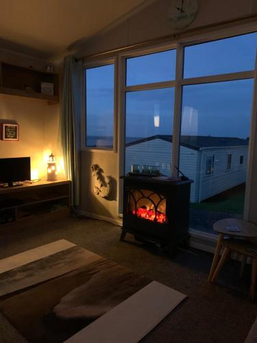 a living room with a fireplace in front of a window at Bliss Beach Lodge Breath taking views in Bembridge