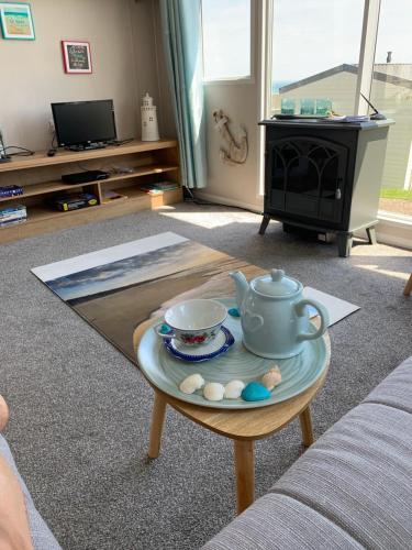 a living room with a coffee table with a tea pot on it at Bliss Beach Lodge Breath taking views in Bembridge