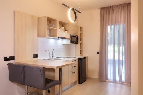 a kitchen with a sink and a counter with chairs at AMMOESSA APARTMENTS in Plataria