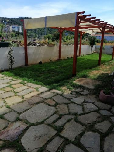 a pergola and a stone patio withgrass at Eceabat Doğa Pansiyon-Hotel in Eceabat