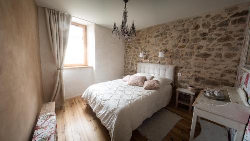 a bedroom with a white bed with pillows and a window at Achilée Les Herbes de la saint Jean in Saint-Bonnet-le-Froid