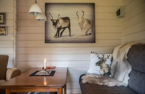 a living room with a table with a candle and animals on the wall at Davvi Siida - Reindeer Design Lodge in Kjøllefjord
