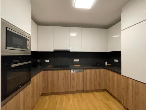 a kitchen with black and white cabinets and a microwave at Modern Danube Apartment Vienna in Vienna