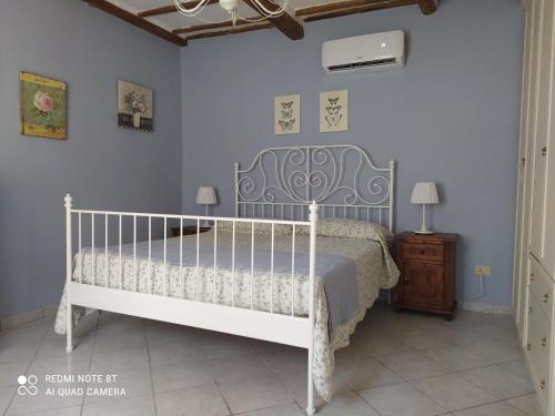 1 dormitorio con cama blanca y pared azul en Alloggio turistico Amalasunta, en San Lorenzo Nuovo