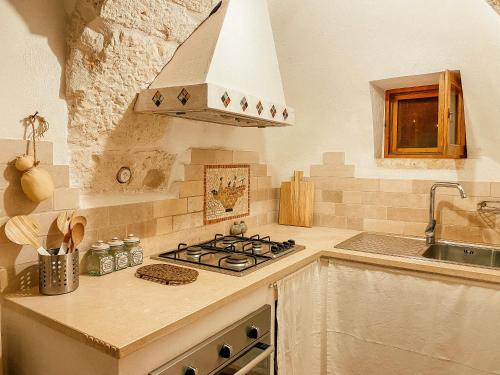 uma cozinha com fogão forno ao lado de um lavatório em Trullo Bianco Ostuni em Ostuni