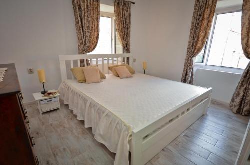a bedroom with a large white bed with windows at Bell Tower Apartment in Budva