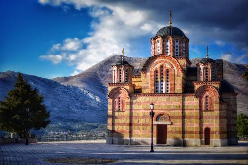 a large brick building with a mountain in the background at Apartman Dajana in Trebinje