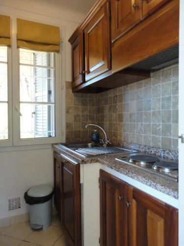 uma cozinha com armários de madeira, um lavatório e uma janela em Villa Playa del Sol - B2 em Saint-Tropez