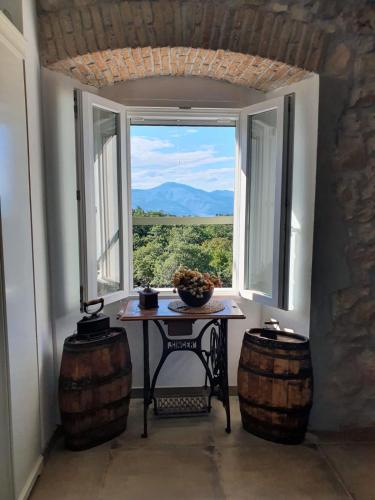 a table in a room with a window and two barrels at Stone House Rosuja in Ivanje