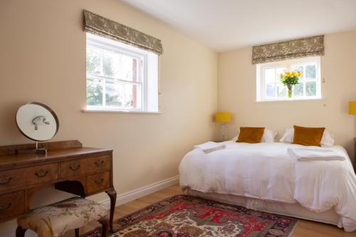 ein Schlafzimmer mit einem Bett, einer Kommode und zwei Fenstern in der Unterkunft Henley Hall, Ludlow in Ludlow