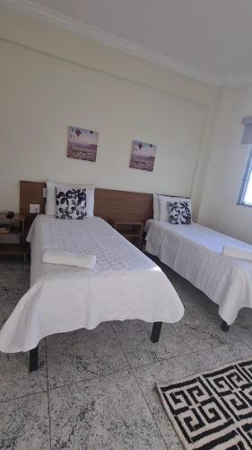 a bedroom with two beds with white sheets and a window at Hotel Flor de Minas in Uberaba