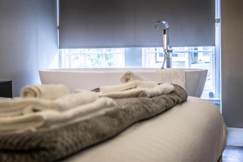 - un lit avec des serviettes blanches et une baignoire dans l'établissement Luxury royal mile boutique 2bedroom apartment, à Édimbourg