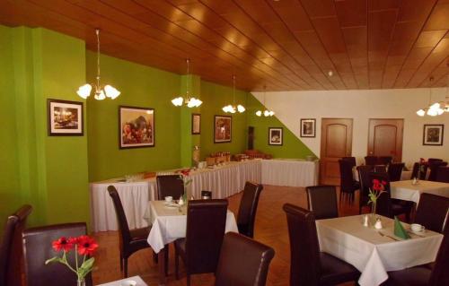 comedor con mesas, sillas y paredes verdes en Hotel garni am Thüringer KloßTheater en Friedrichroda