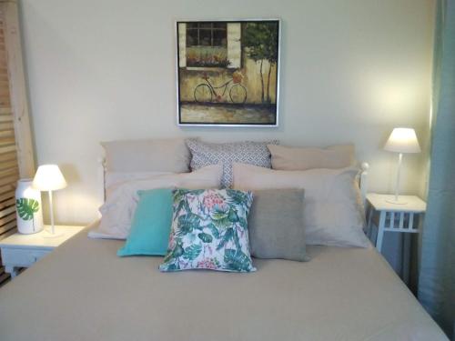 a bed with pillows and a painting on the wall at blue cielo sunny apartment in Palaiá Fókaia