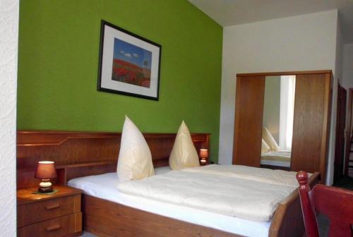 ein Schlafzimmer mit einem Bett mit einer grünen Wand in der Unterkunft Hotel garni am Thüringer KloßTheater in Friedrichroda