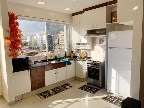a kitchen with white cabinets and a large window at IDEAL ESPECIAL FAMILIAR in Cochabamba