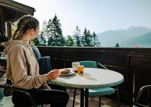 a woman sitting at a table with a plate of food at Mountain Hotel & Hostel in Ramsau am Dachstein