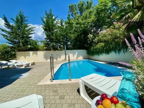 a swimming pool with a bowl of fruit on a table next to it at Private pool and Mediterranean garden apt Mia in Šilo