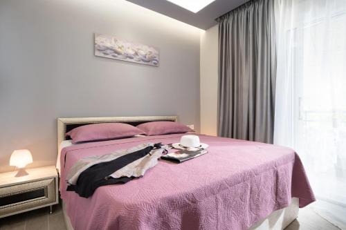 a bedroom with a pink bed with a tray on it at Leonardo Apartamente in Toroni
