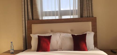 a bed with a wooden headboard with red and white pillows at Walabi Mara Hotel in Narok