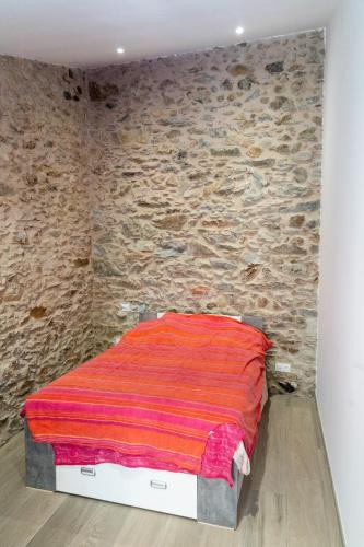 un lit dans une chambre avec un mur en pierre dans l'établissement Maison 3ch 65m2 en bord de mer, à Banyuls-sur-Mer