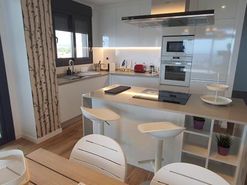 a kitchen with a counter and stools in it at Sunset Waves Benidorm by KalmaRent in Benidorm