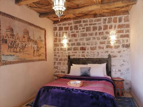 Ce lit se trouve dans une chambre dotée d'un mur en briques. dans l'établissement Chambre d'hôtes aya, à Ouzoud