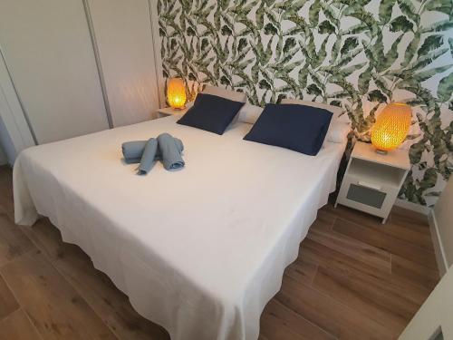 a white bed with two blue pillows on it at Sunset Waves Benidorm by KalmaRent in Benidorm