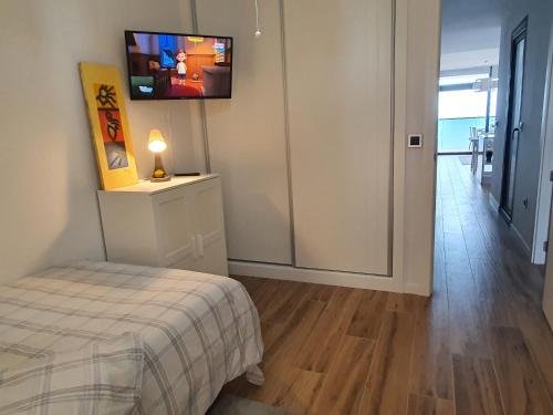 a bedroom with a bed and a television on a wall at Sunset Waves Benidorm by KalmaRent in Benidorm