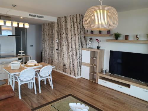 a living room with a table and a flat screen tv at Sunset Waves Benidorm by KalmaRent in Benidorm