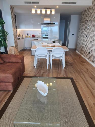 a living room with a table and chairs and a kitchen at Sunset Waves Benidorm by KalmaRent in Benidorm