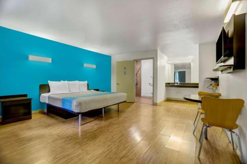 1 dormitorio con cama y pared azul en Motel 6-Anderson, CA - Redding Airport, en Anderson