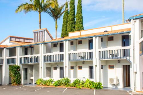 a large white building with palm trees in the background at The Tauranga on the Waterfront in Tauranga
